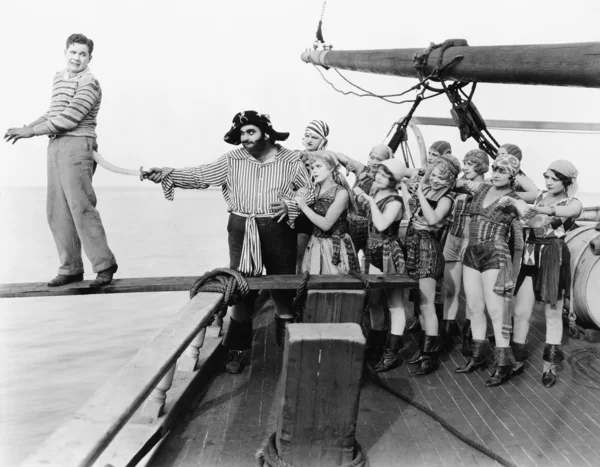 Grupo de piratas tentando empurrar um jovem sobre uma prancha — Fotografia de Stock