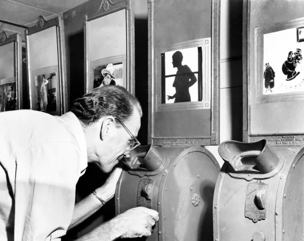 Mężczyzna patrząc na maszynę filmie nickelodeon — Zdjęcie stockowe