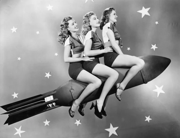 Three women sitting on a rocket — Stock Photo, Image