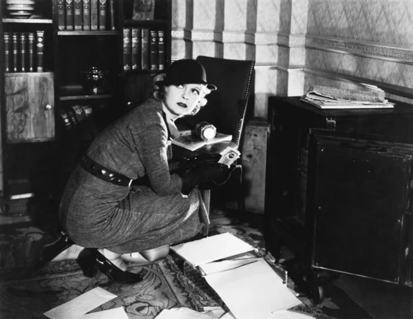 Jeune femme dans un bureau à côté d'un coffre-fort, regardant par-dessus son épaule — Photo