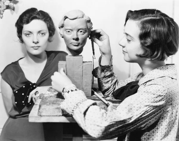 Mujeres y un artista de pie juntos mientras uno está trabajando en un busto —  Fotos de Stock