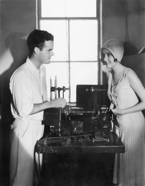 Mujer sonriendo a un hombre al lado de una máquina de edición — Foto de Stock