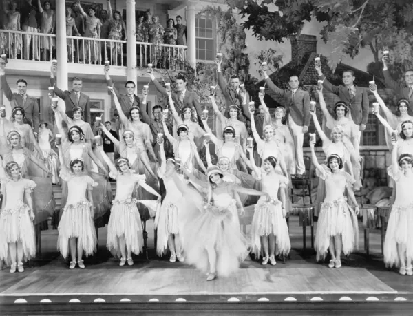 Группа танцоров, стоящих на сцене с поднятыми руками и выпивкой в руках — стоковое фото