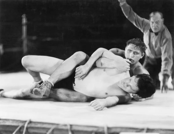 Due uomini che lottano con un arbitro sullo sfondo — Foto Stock
