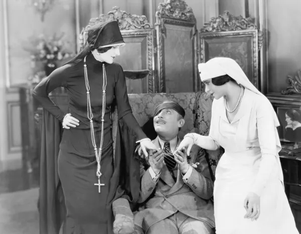 Jovem com um pala de olho sendo consolado por uma enfermeira e uma mulher religiosa — Fotografia de Stock