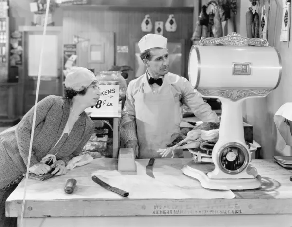 Mujer de pie en una carnicería mirando la balanza — Foto de Stock