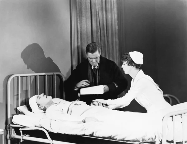 Arts en verpleegkundige aanwezig zijn bij een patiënt in een ziekenhuisbed — Stockfoto