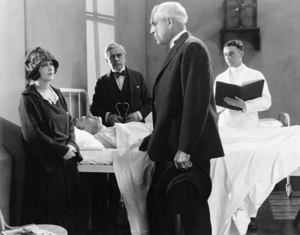 Доктор разговаривает с молодой женщиной в больничной палате больного пациента — стоковое фото