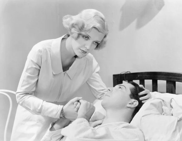 Bir adam bir hastane yatağında teselli hemşire — Stok fotoğraf