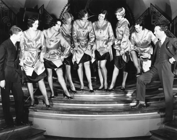 Uma linha de coro de mulheres mostrando suas pernas para dois homens — Fotografia de Stock