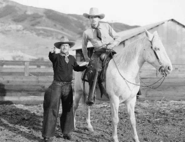Twee cowboys en een wit paard — Stockfoto