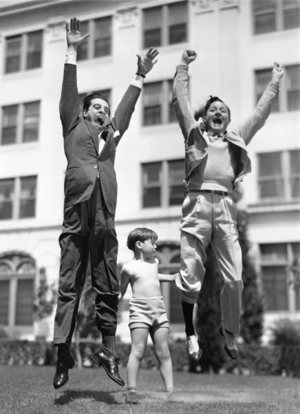 Malý chlapec, který předstírá, že zvednout dva dospělí muži — Stock fotografie
