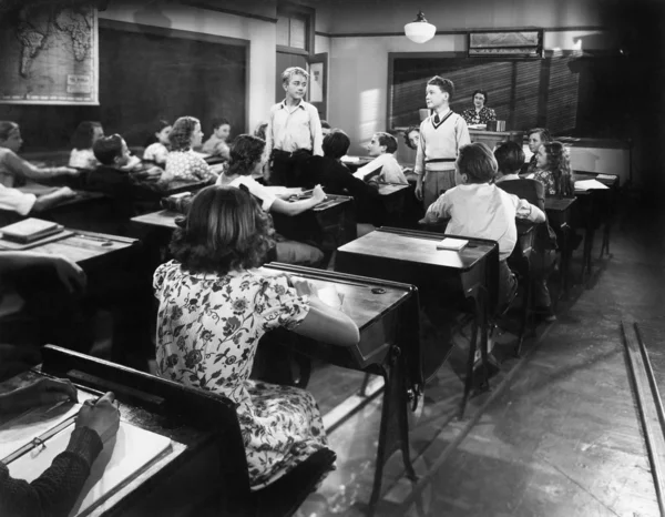 Τα παιδιά σε ένα δωμάτιο κατηγορίας με ένα δάσκαλο και δύο αγόρια κοιτάζοντας ο ένας τον άλλον — Φωτογραφία Αρχείου