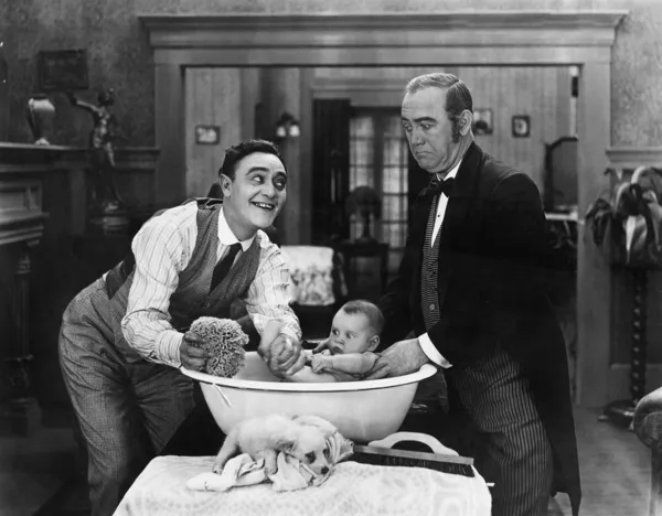 Twee mannen geven een baby van een bad — Stockfoto
