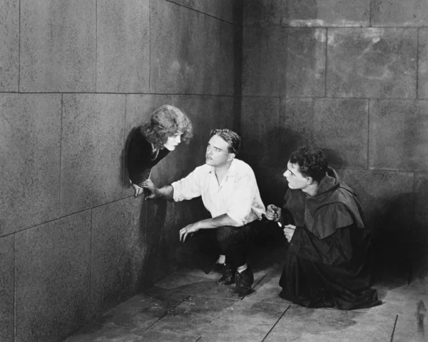 Um padre e um homem tentando ajudar uma jovem mulher a escapar — Fotografia de Stock