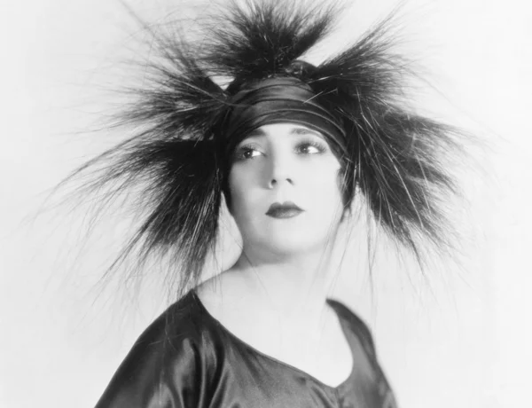 Elegante jonge vrouw op zoek serene in een veer hoed — Stockfoto