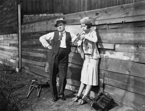 Frau übt Trompete, während ein Mann neben ihr steht und genervt guckt — Stockfoto