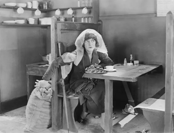 Jonge vrouw die zit in een cabine in een diner, proberen te stelen iets uit een jute zak — Stockfoto