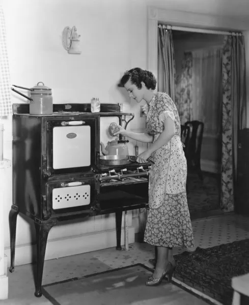 アンティーク ストーブで調理の女性 ストック画像