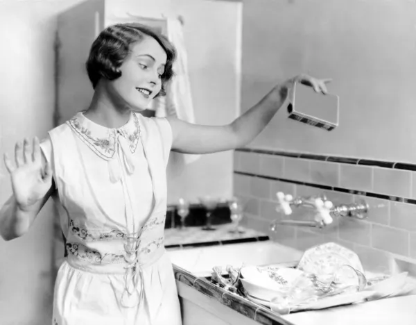 Frau gießt Seife auf Geschirr Stockbild