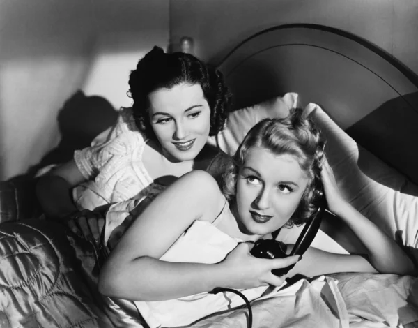 Two women in bed with telephone Stock Photo