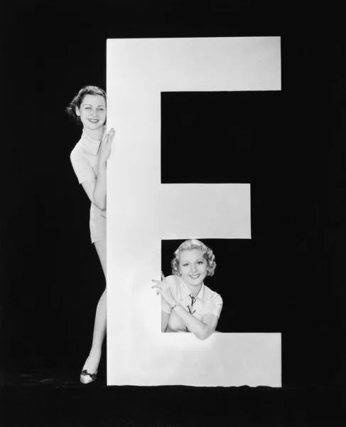 Mujeres posando con enorme letra E Imagen de stock