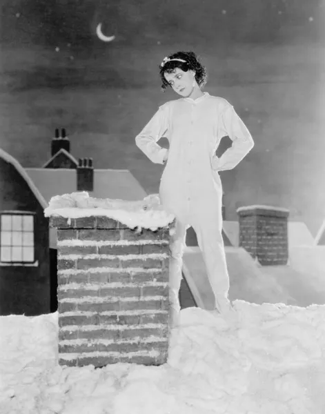 年轻女子看雪屋顶上的烟囱 — 图库照片#