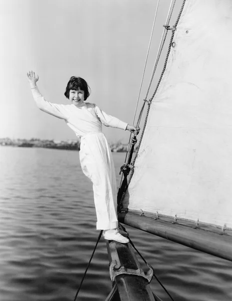 Chica joven de pie en un velero y saludando Imagen De Stock