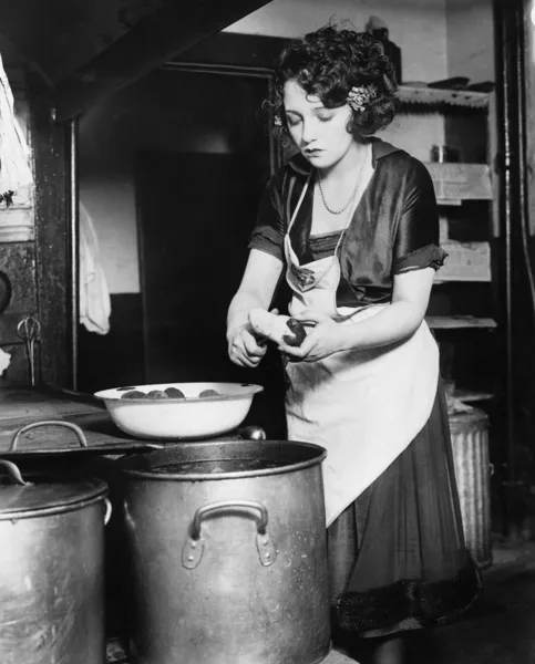 Kadın bir mutfak patates soyma Stok Fotoğraf