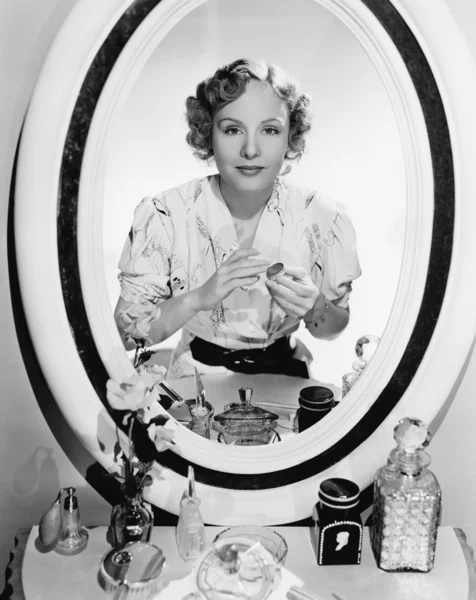 Mujer sentada frente a su vanidad mirando al espejo Imagen de archivo