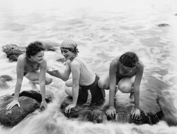 Drei Frauen spielen im Wasser am Strand lizenzfreie Stockfotos