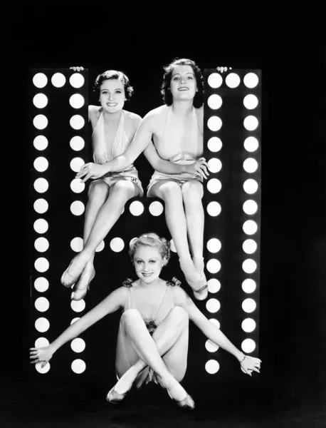 Tre unga kvinnor poserar med bokstaven h Stockfoto