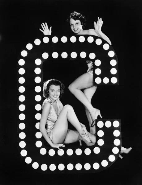 Två unga kvinnor poserar med bokstaven c Royaltyfria Stockfoton