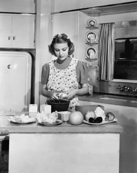 Junge Frau bereitet Essen in der Küche zu Stockbild