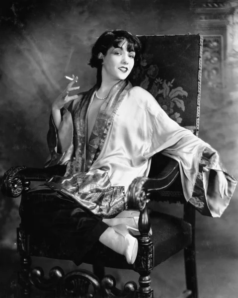 Porträt einer jungen Frau, die eine Zigarette raucht und lächelt lizenzfreie Stockfotos