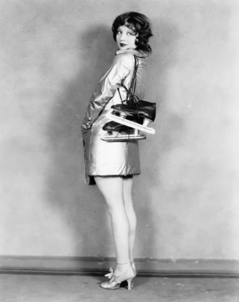 Profil av en ung kvinna som bär skridskor på hennes axlar Stockbild