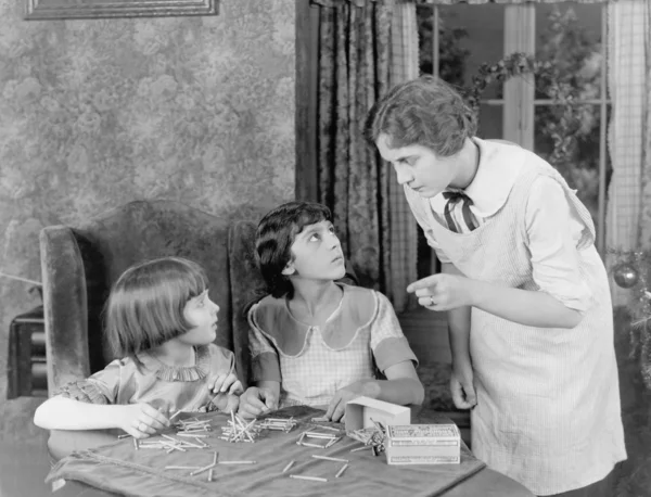 Vrouw haar twee dochters scolding voor het spelen met lucifers Stockfoto