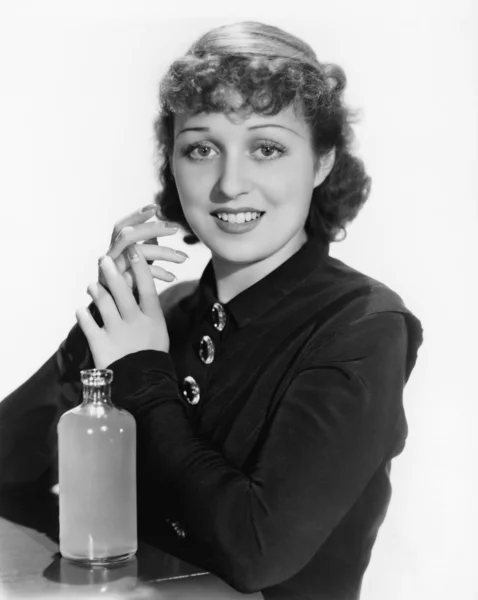 Πορτρέτο του μια νεαρή γυναίκα με ένα μπουκάλι χαμογελώντας Εικόνα Αρχείου