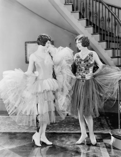 Två kvinnor tittar på varandras klänningar Stockbild