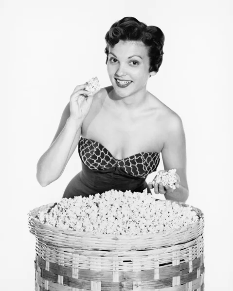 Portrait of a young woman showing popcorn and smiling Stock Picture