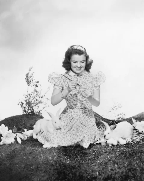 ウサギのイースターエッグを塗ると草の上に座っていた若い女性 ストック写真