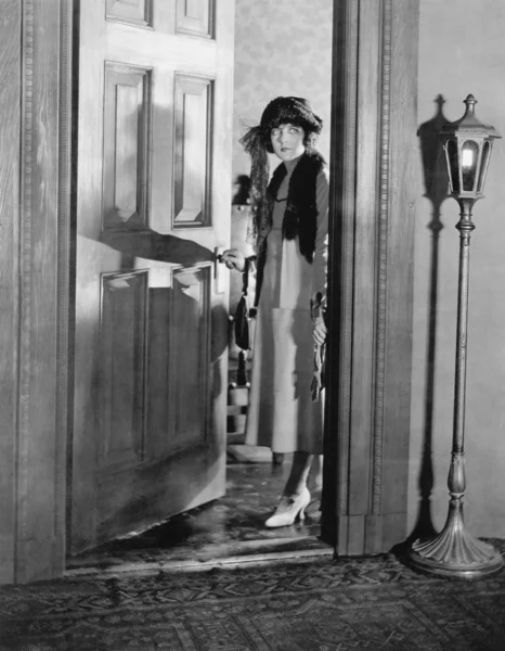 Vrouw gekleed in de deuropening staan Stockfoto