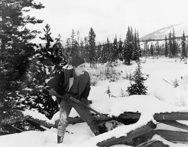 Jäger läuft mit Gewehr durch verschneite Landschaft — Stockfoto