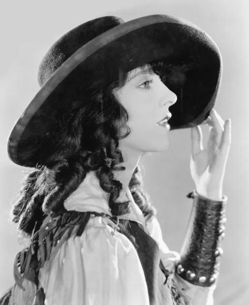 Profiel van een jonge vrouw met krullen in een grote hoed Stockafbeelding