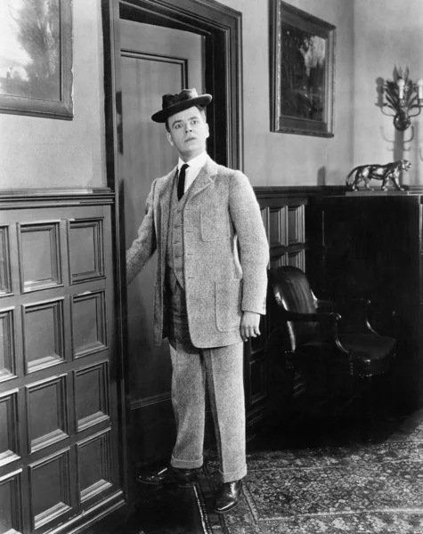Hombre con sombrero que parece tonto entrando en una habitación Imagen de archivo