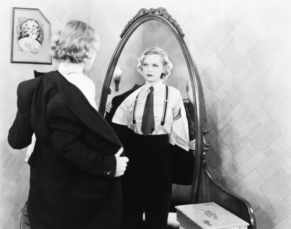 Jeune femme habillée en homme se déshabille devant un miroir Photos De Stock Libres De Droits