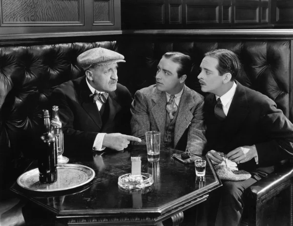 Three men sitting together at a bar Stock Picture