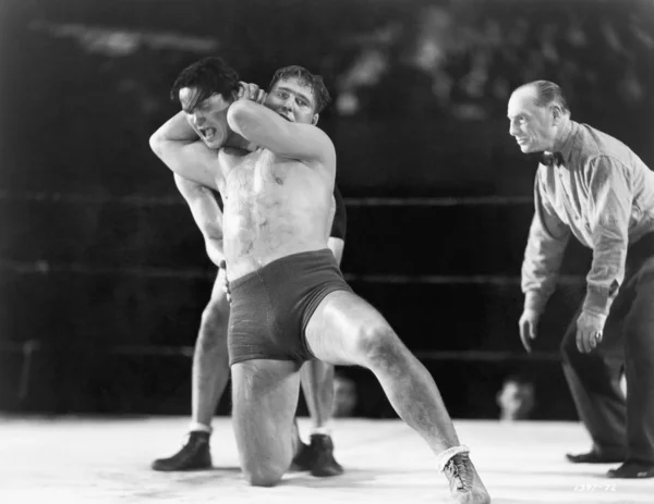 Due uomini che lottano con l'arbitro facendo una chiamata sullo sfondo — Foto Stock