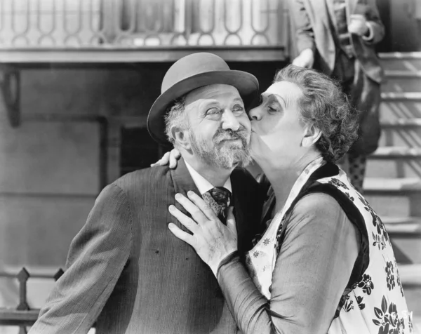 Woman kissing a man on his cheek Stock Image