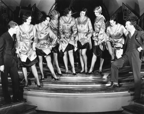 Una línea de coro de mujeres mostrando sus piernas a dos hombres — Foto de Stock